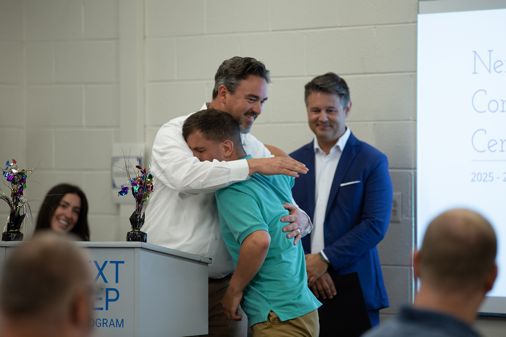 A staff member hugs a student during Next Step's completion ceremony
