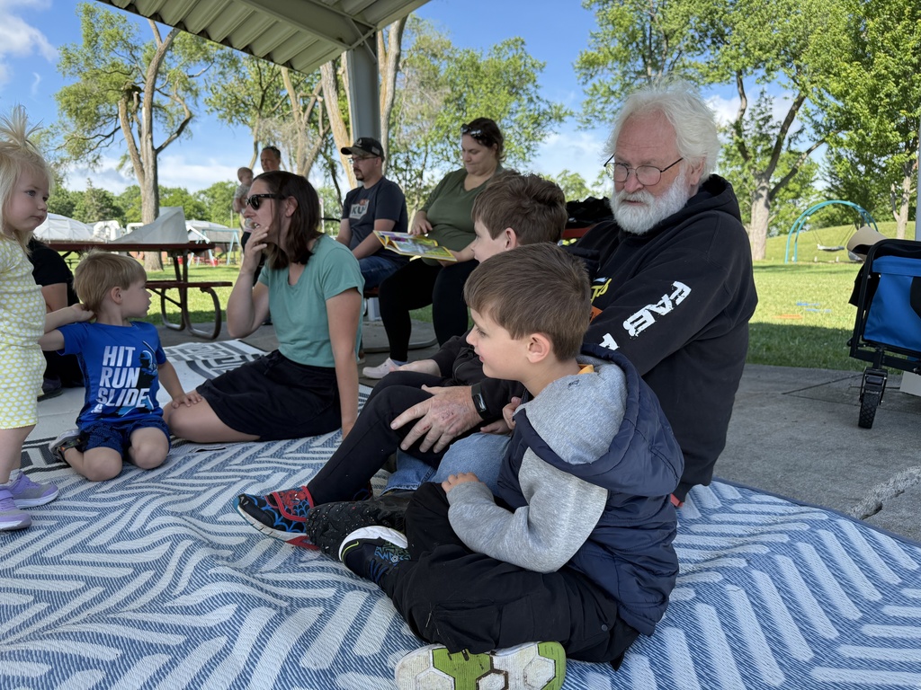 Caregivers and children sit on a rug at Marsyville Park