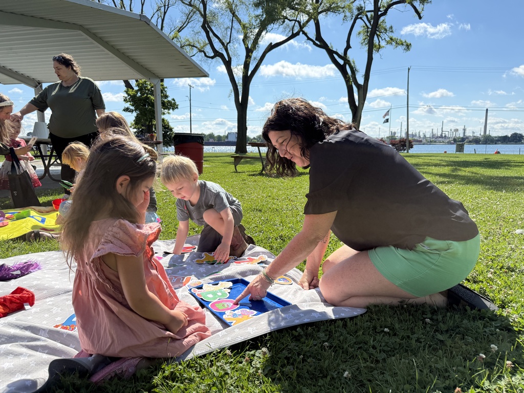 RESA's Jennifer Gunderson sits on a colorful blanket and engages in a letter activity with a child