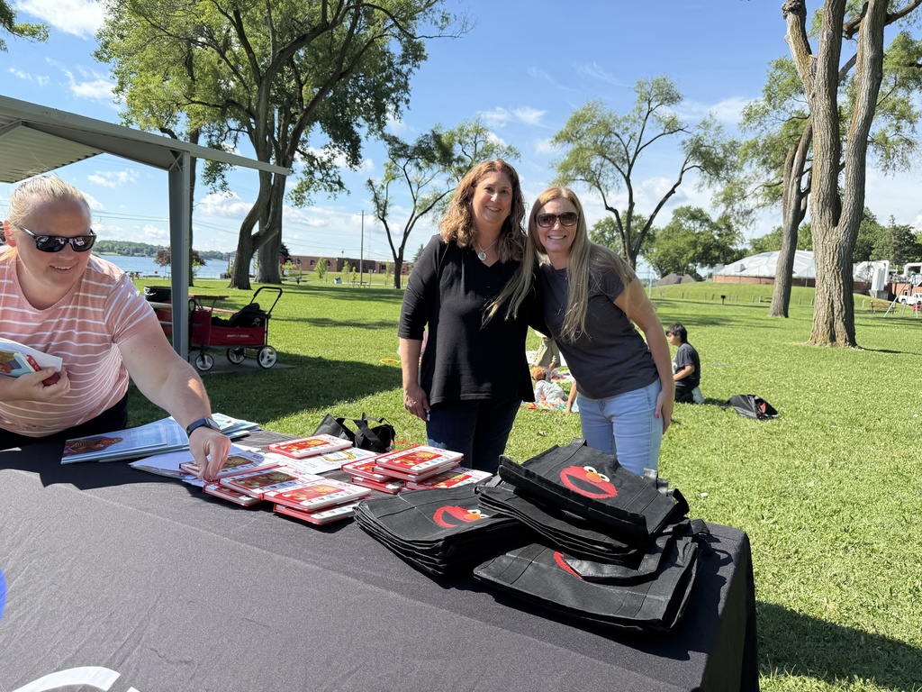 Early Childhood Services Director Becky Gorinac and Tara from PBS pose behind a table full of books and giveaways