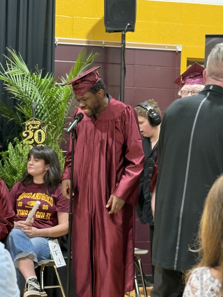 Completer Tyrique stands at a microphone while singing a solo during the Completion Ceremony
