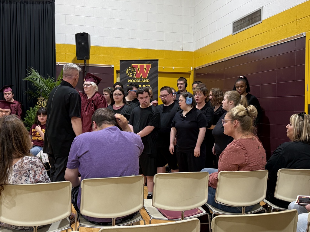 The Woodland Choir, dressed in all black, sings under the direction of Alan Demski