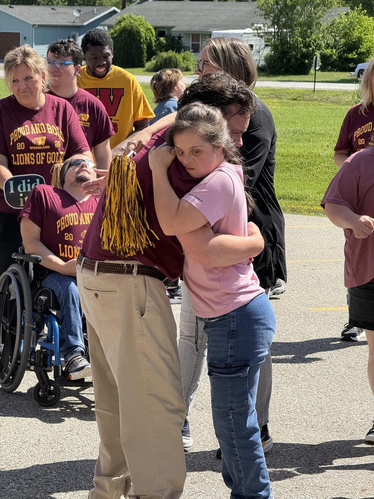 A student hugs completer Adam in front of the school.