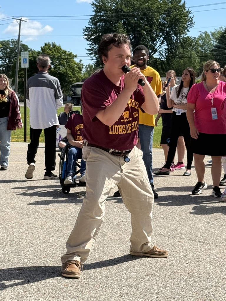 A Woodland completer sings into a microphone in front of the school