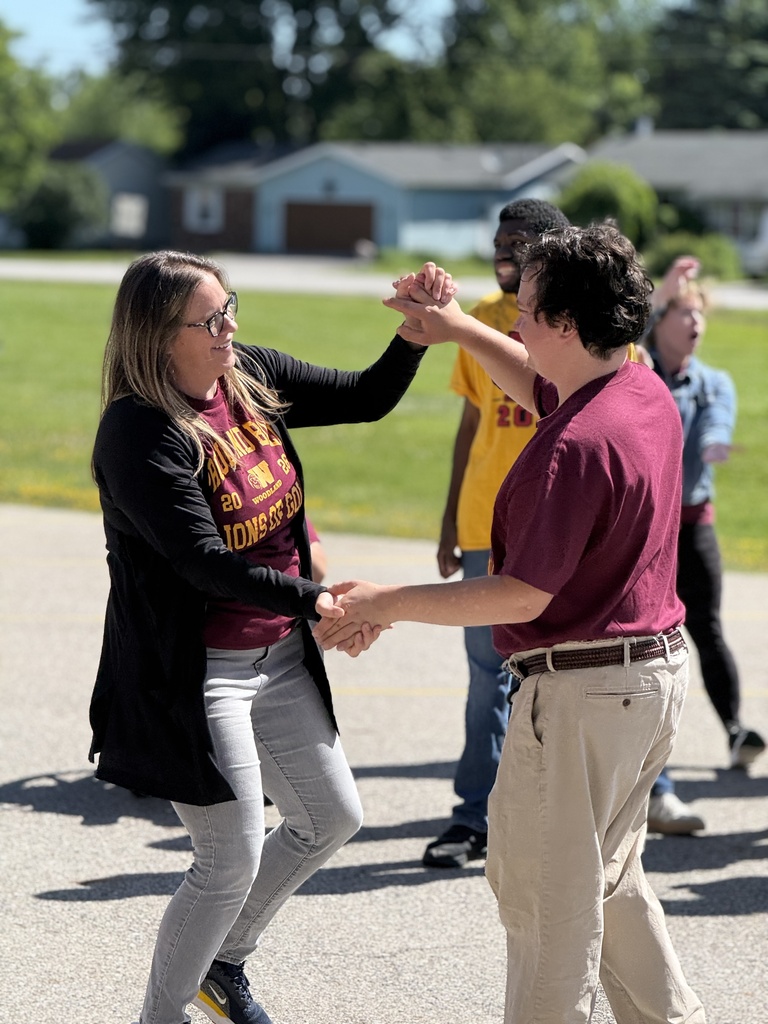 Principal Cora Heyboer dances with completer Adam hand-on-hand in front of the school