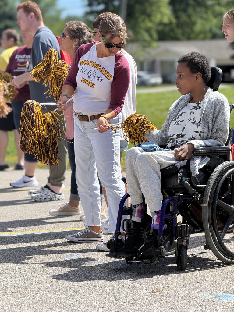 Staff and students wave pom-poms in front of the school