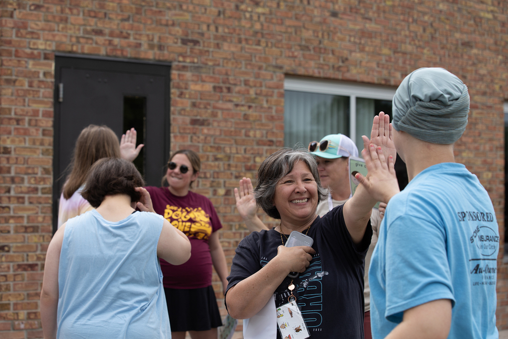 Three Woodland staff members high-five students during the school's field day