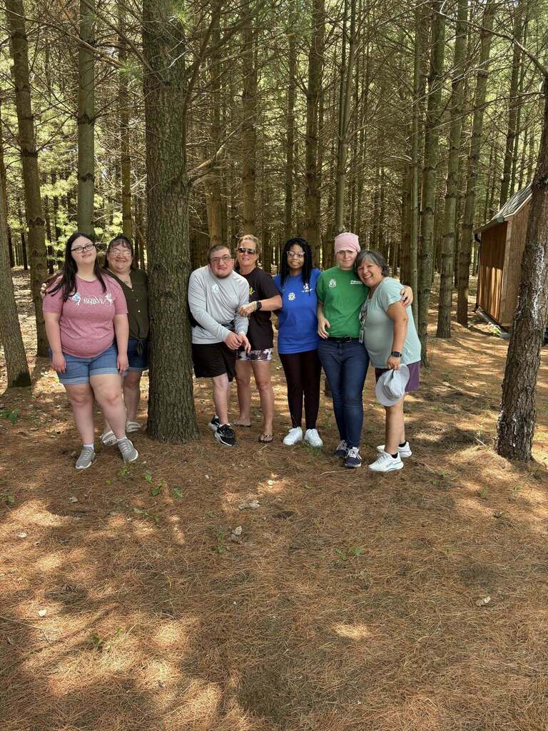Woodland staff and students pose outside surrounded by trees