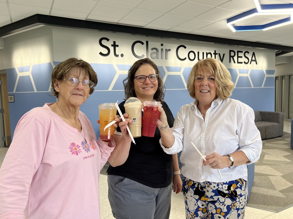 Three RESA staff members holding McDonalds beverages pose in the RESA Administration Building lobby