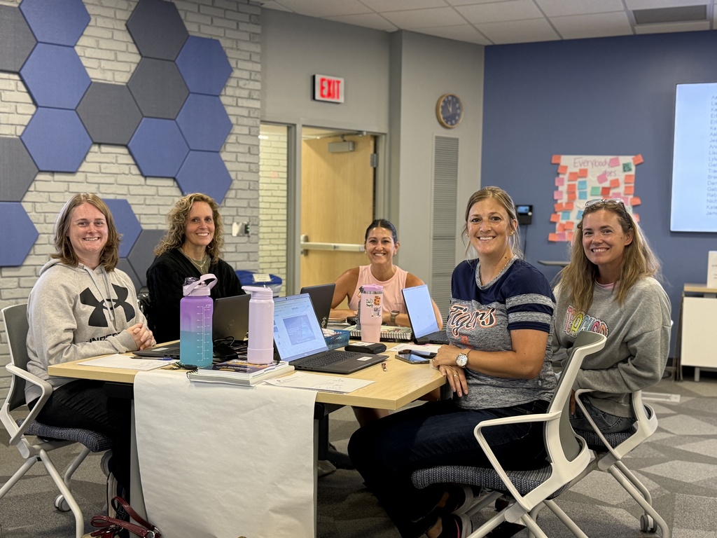 Five educators seated at a table smile for the camera