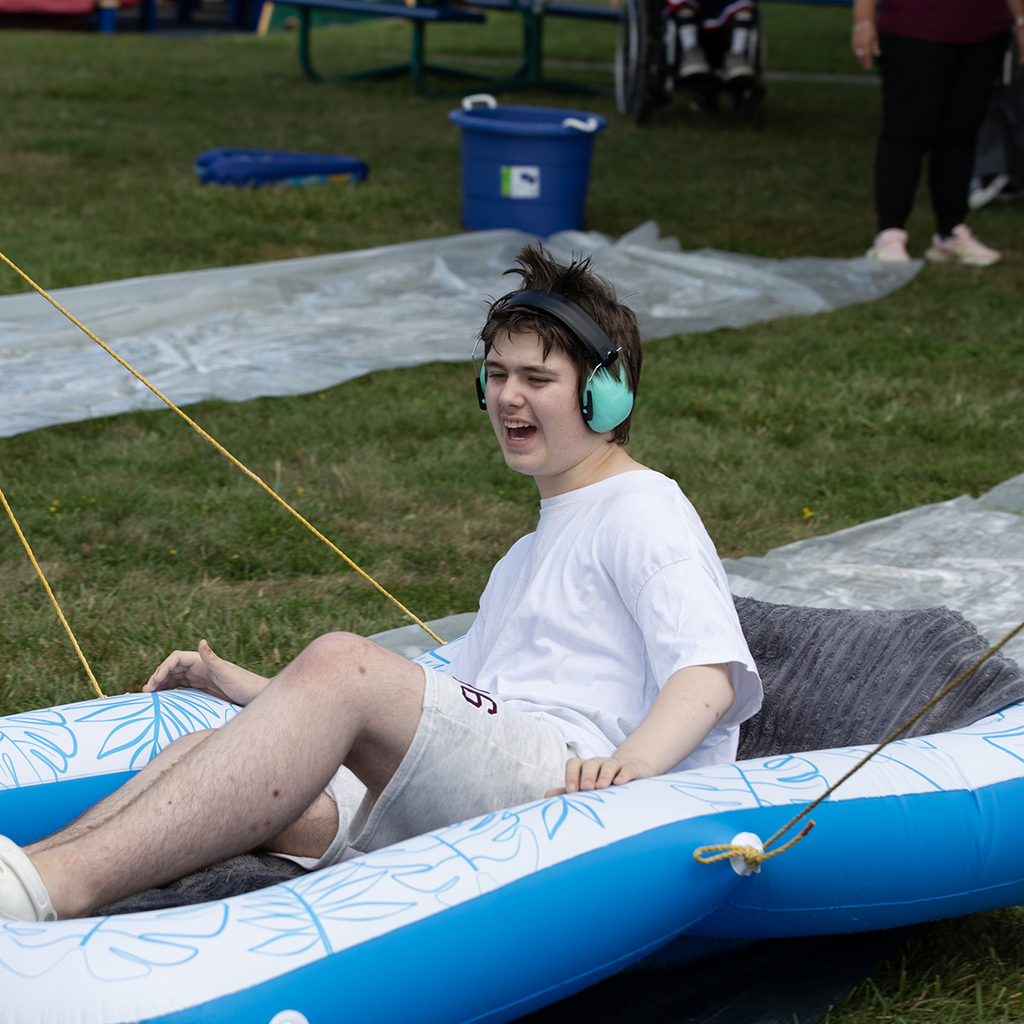 A Woodland student sits in an inflatable raft being pulled by staff members