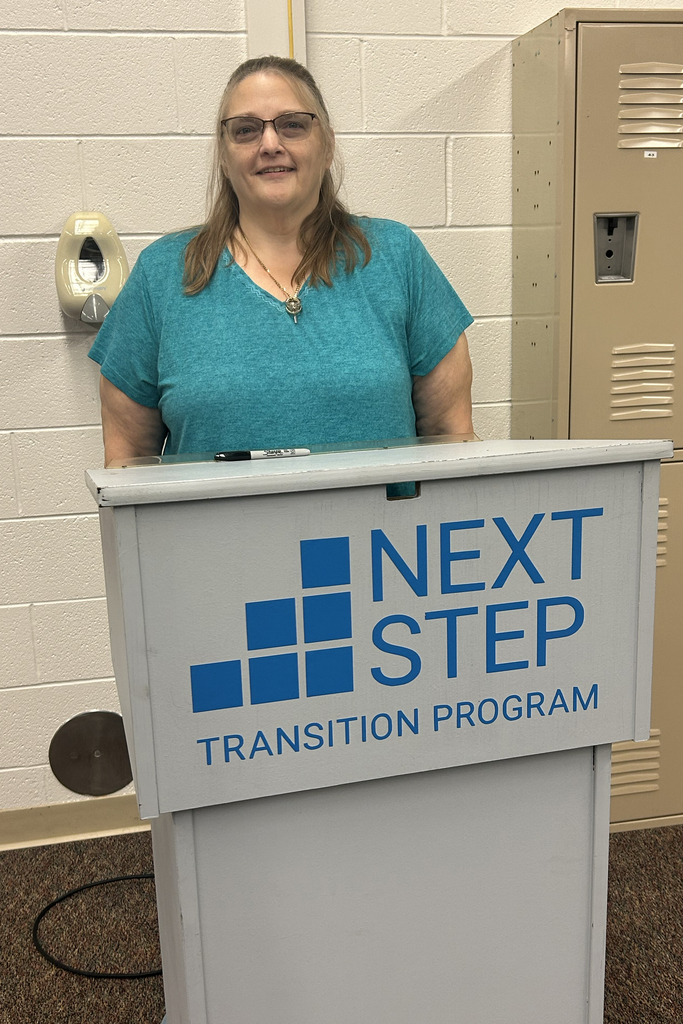 Laurie Cassar stands behind a lectern at the Next Step Transition Program
