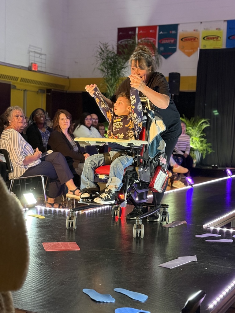 A Woodland staff member holds a the arms up in the air. The student is seated in a wheelchair.