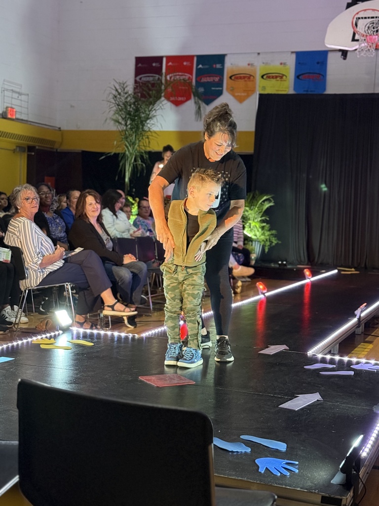 A Woodland staff member holds on to a student dressed in camo pants blue sneakers, and a zip up cardigan