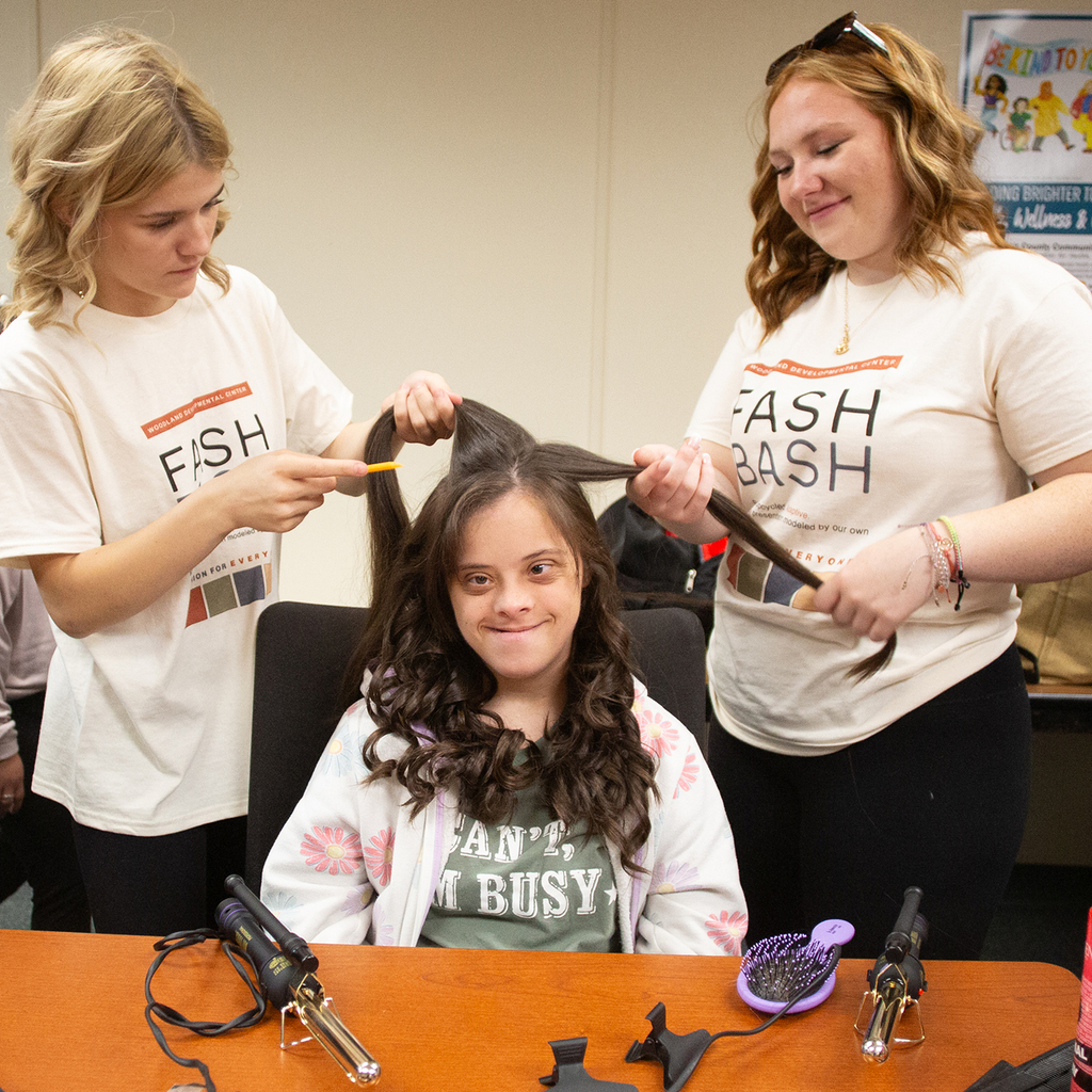 Two Cos students curl a Woodland student's hair
