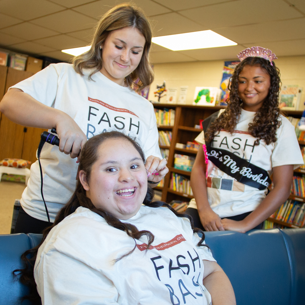 A Cos student curls the hair of a Woodland student