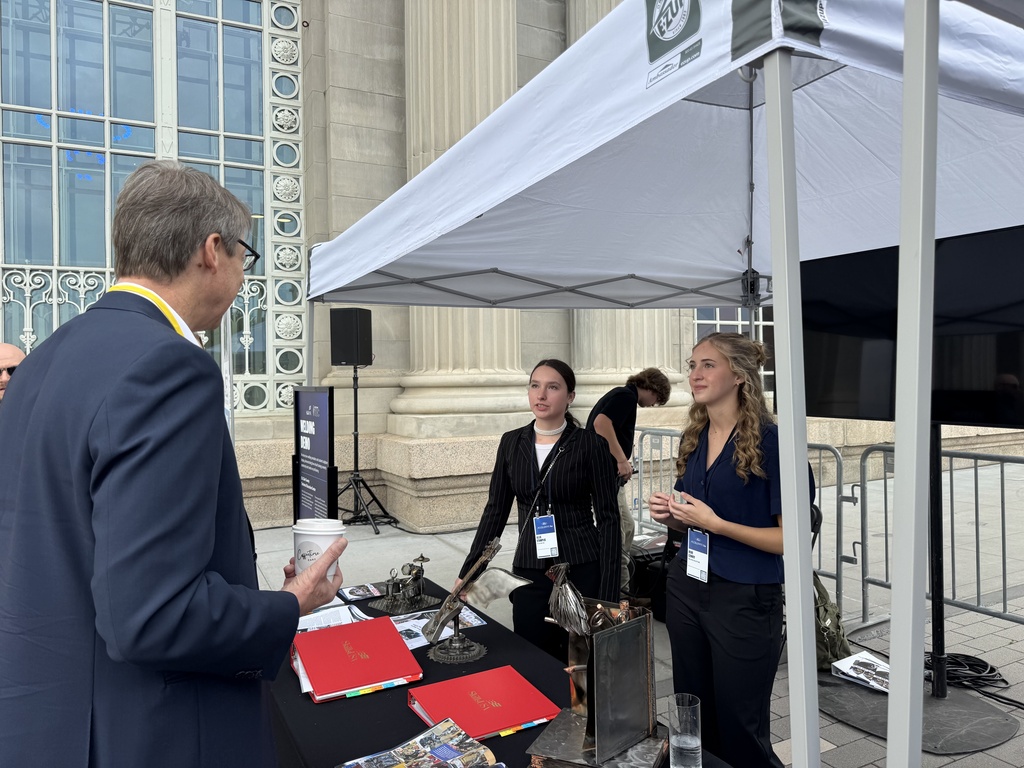 Students Allie Stamplis and Rori Cowhy talk with an attendee at Ford Accelerate