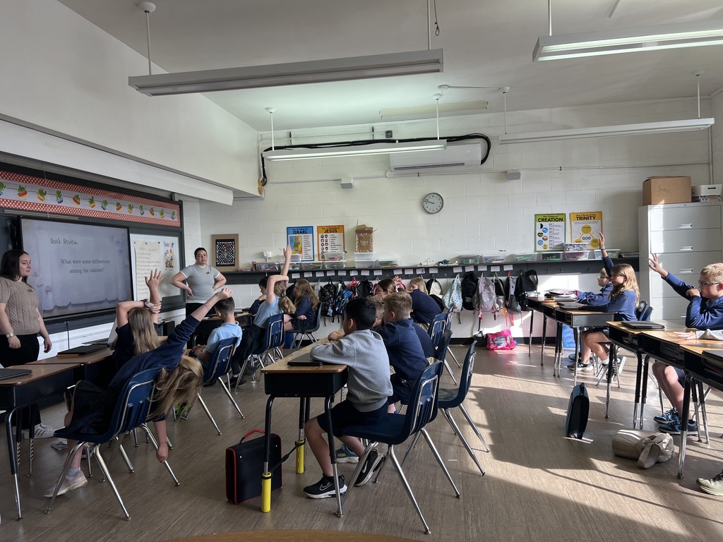 Bellarmine Students at St Edward’s designed and led lessons for our students in grades 2 through 5, this image is of Students raising hands during a classroom lesson.
