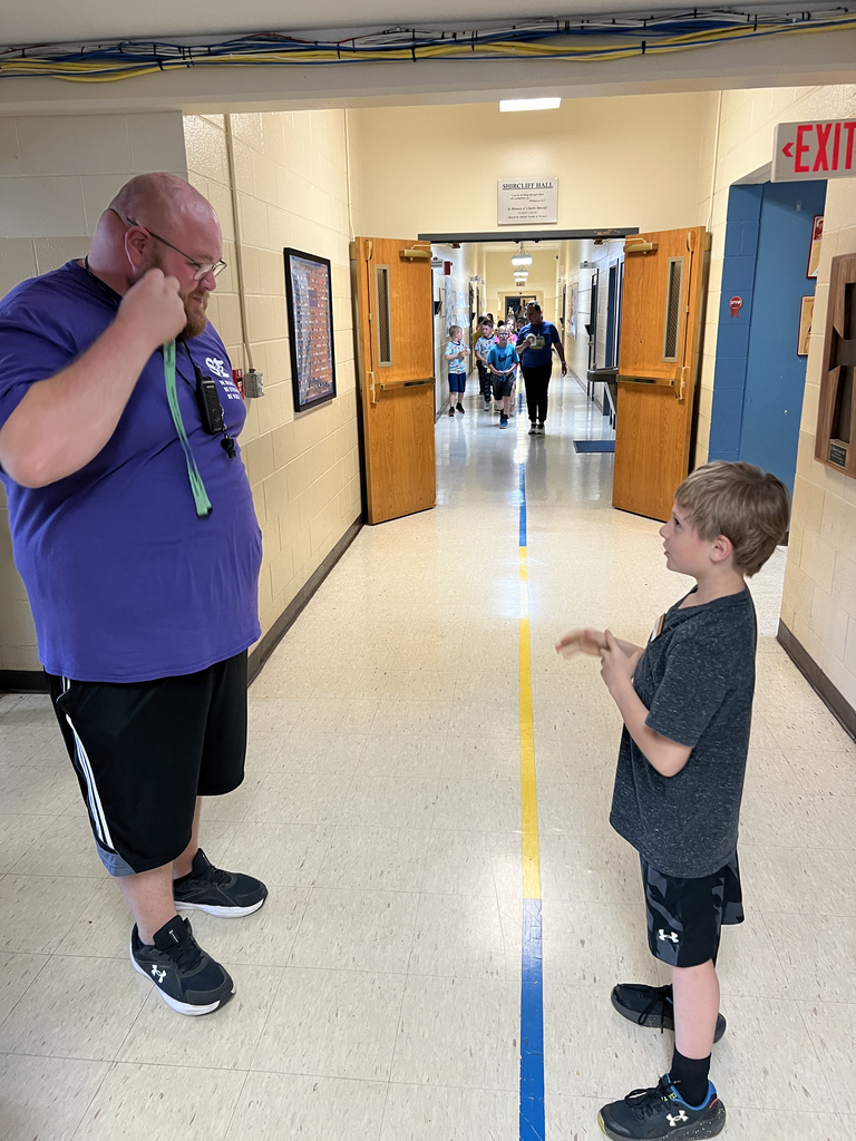 Student speaking with a sports teacher in the hallway.