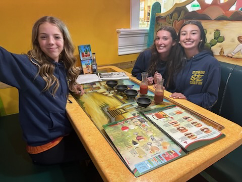Three students sitting at a restaurant table.
