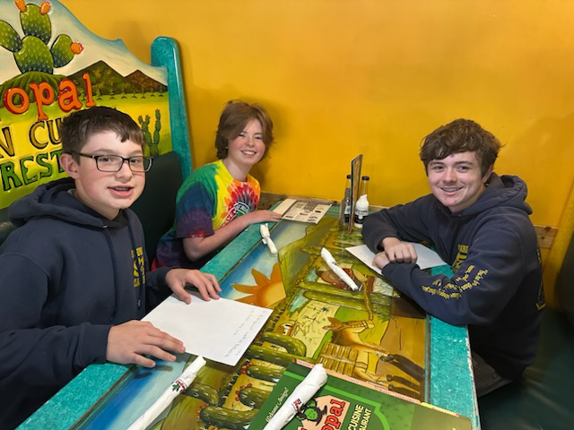 Three students seated at a restaurant table.