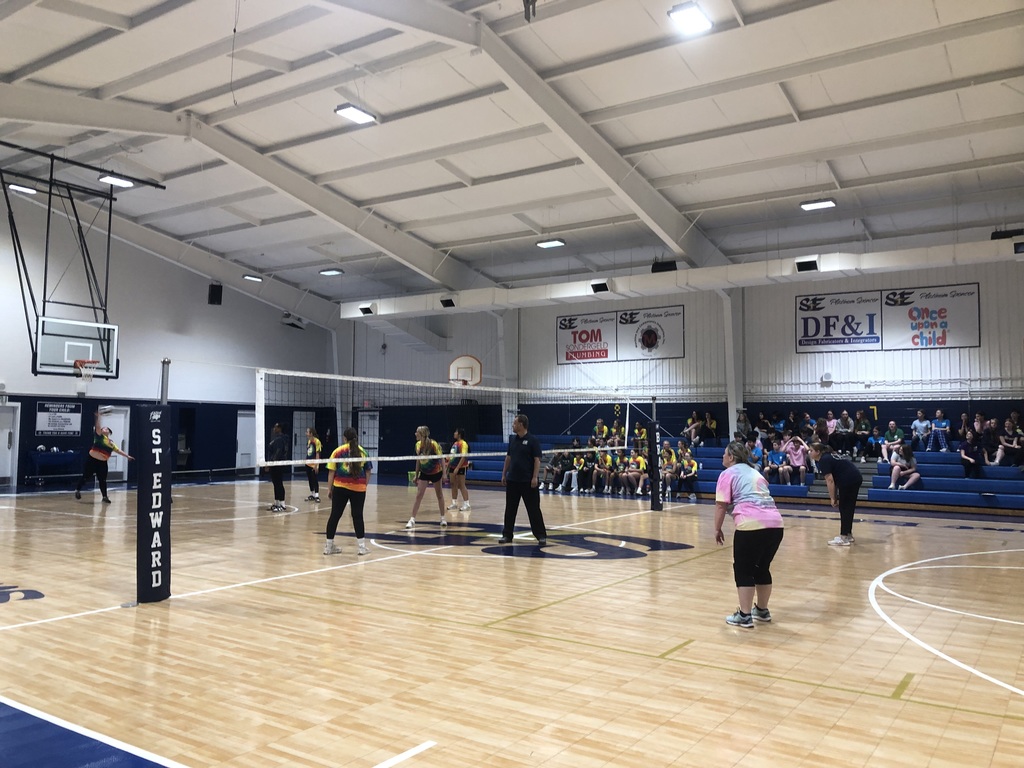 Eighth grade and faculty teams playing volleyball in the gym.