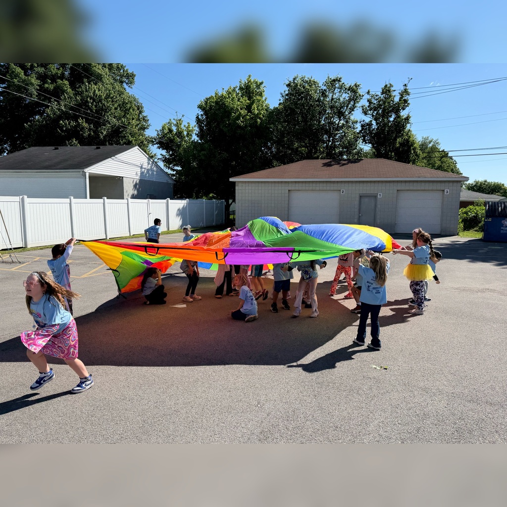 Students playing with a colorful parachute outside.