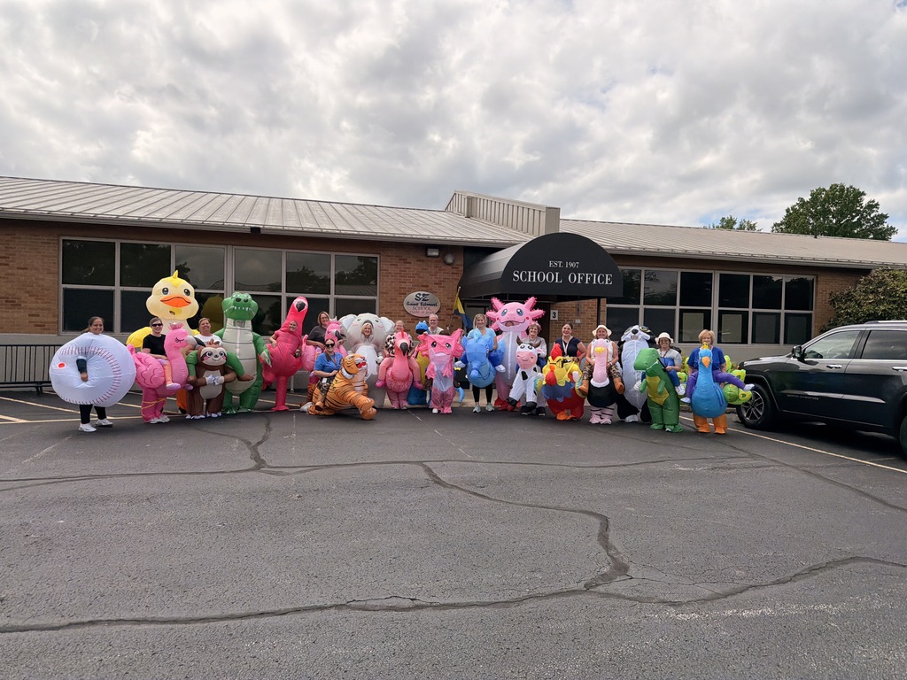 Staff members posing in inflatable costumes outside school.