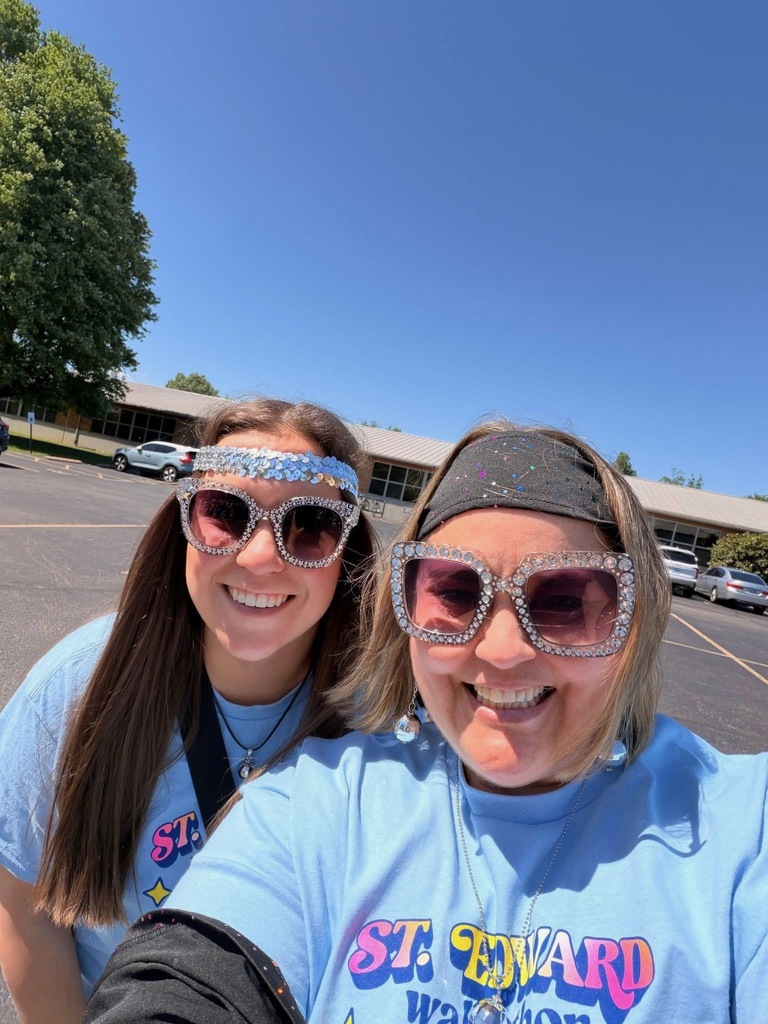 Two St. Edward staff members smiling in matching Walkathon shirts and fun glasses.