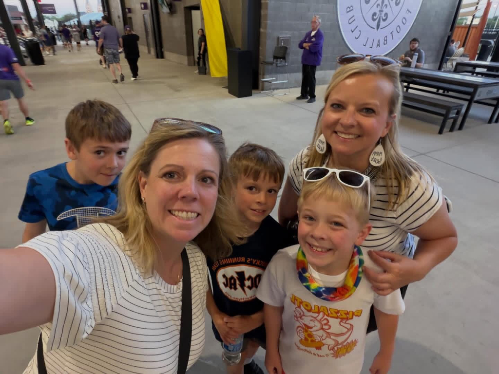 Moms and sons smiling together inside the LouCity stadium.