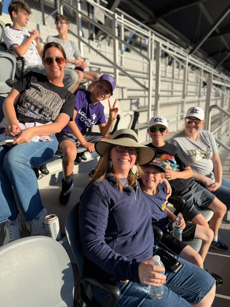 Mothers and sons smiling together in the stands at the LouCity soccer game.