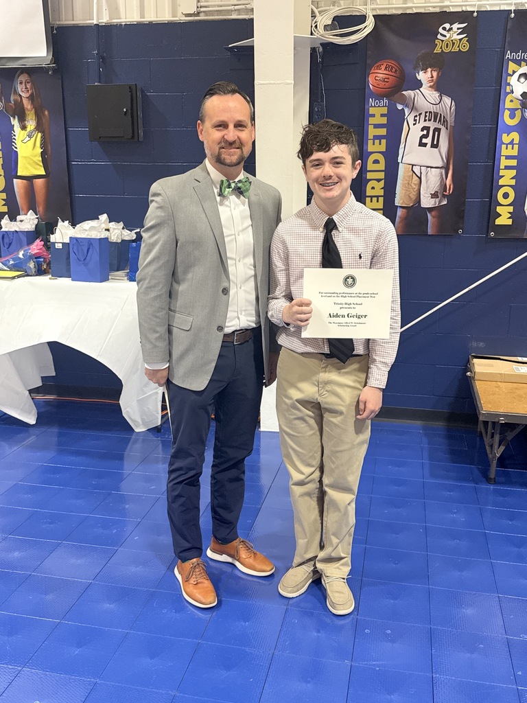 Trinity High School award recipient smiles with the representative of the school while holding his certificate.