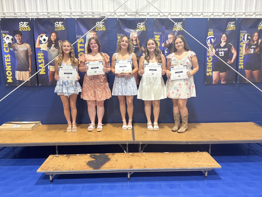 Five St. Edward 8th grade students stand together on stage holding Principal’s Award certificates.