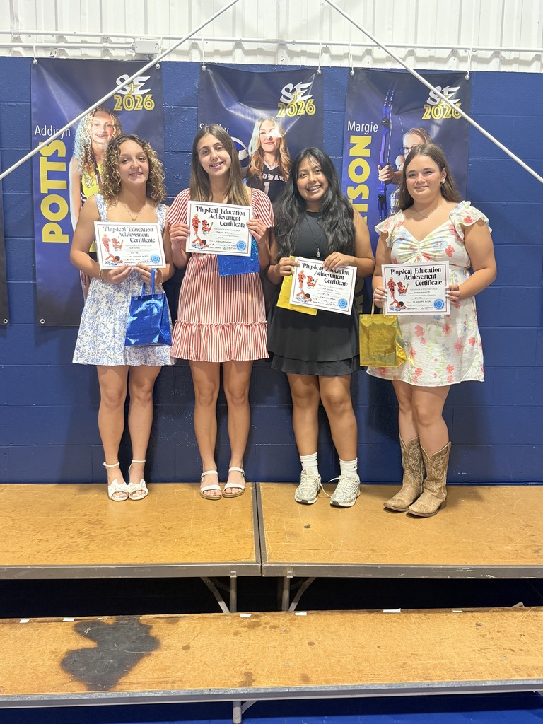 Four 8th grade students stand together holding Physical Education Achievement Certificates.