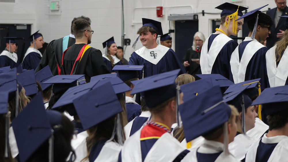 graduate shaking hands with teacher after receiving diploma