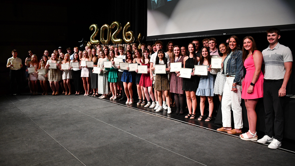 large group of students on a stage holding certificates