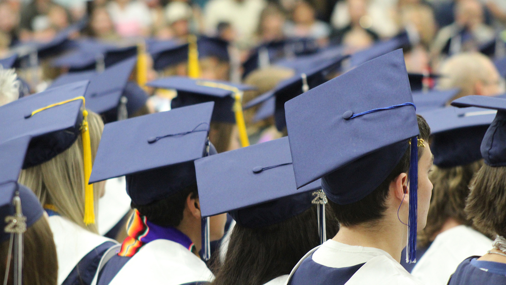 rows of students in graduation attire with the focus on multiple graduation caps