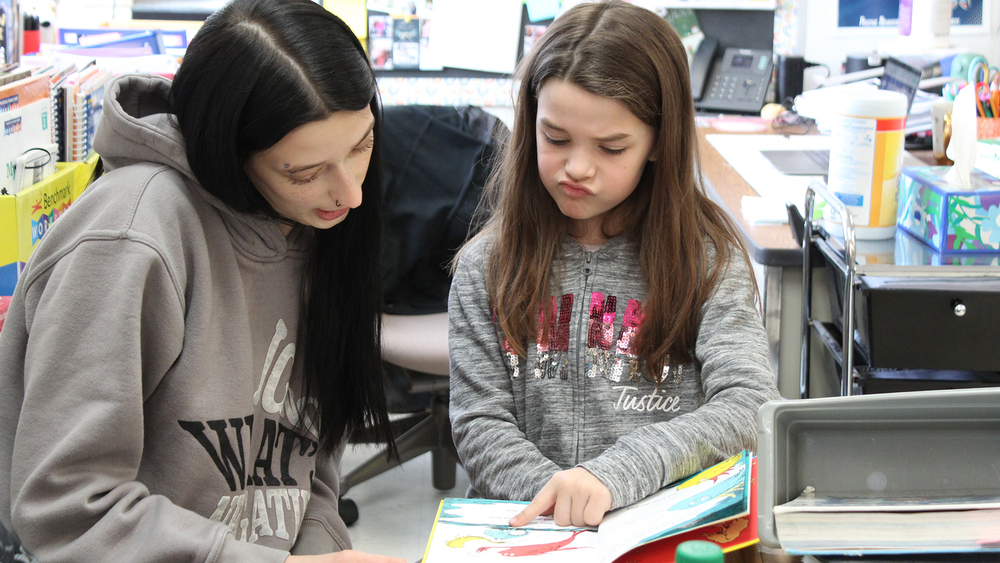 older student reading with younger student