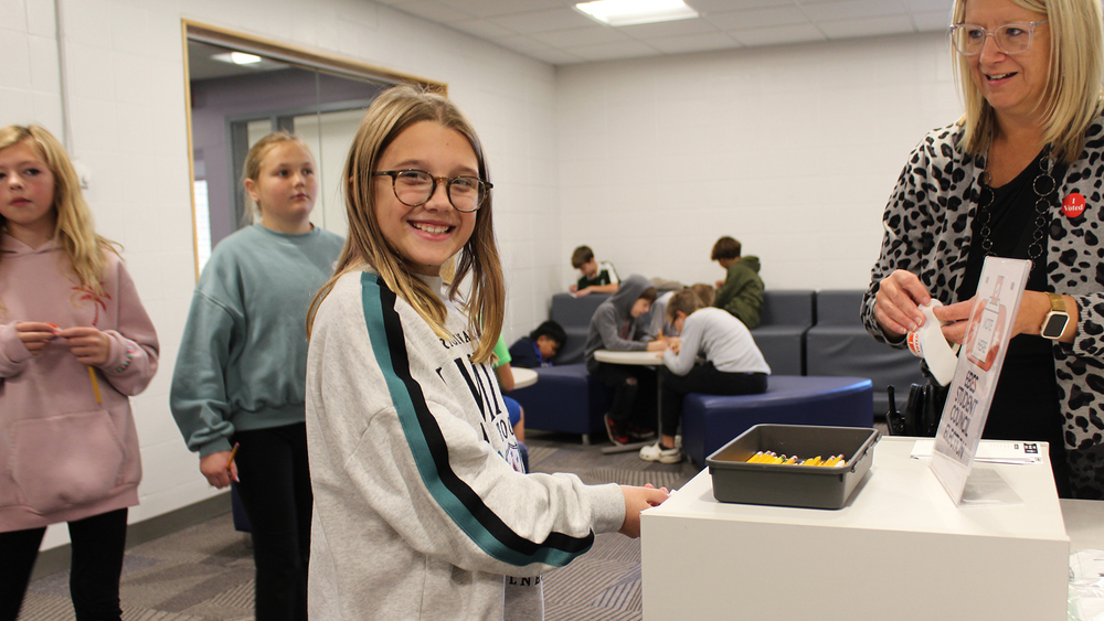 student placing ballot in box