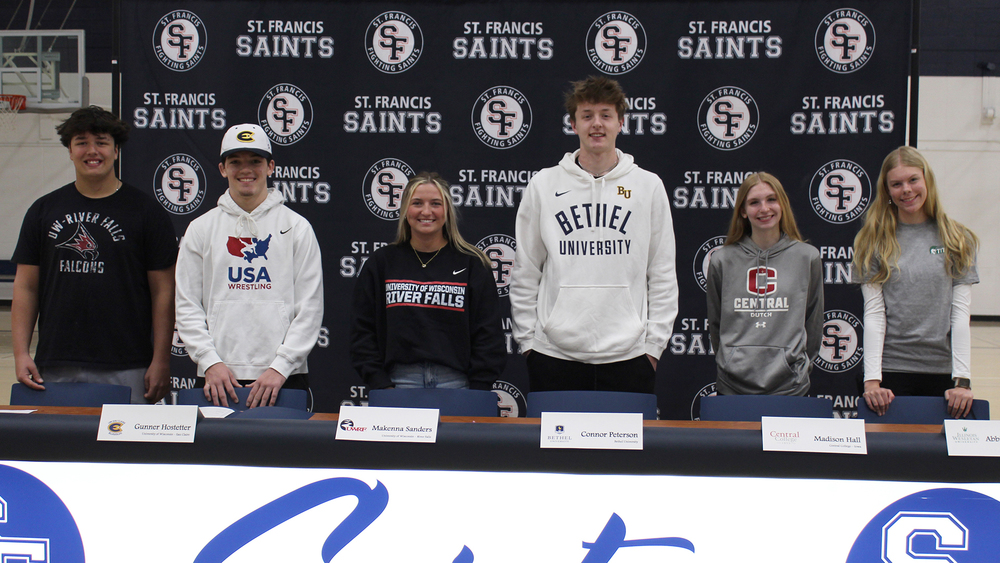 six signees at a press table