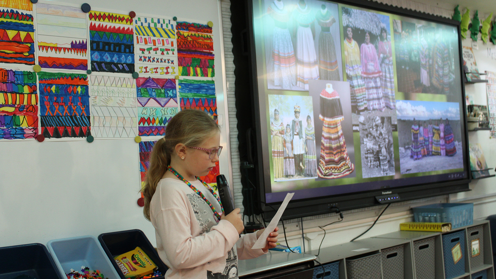 student talking from mic in front of class