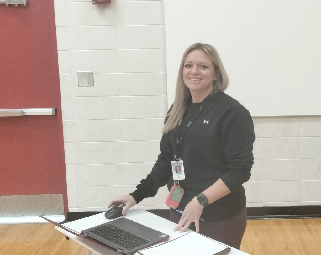 Coach stands at her computer smiling. 