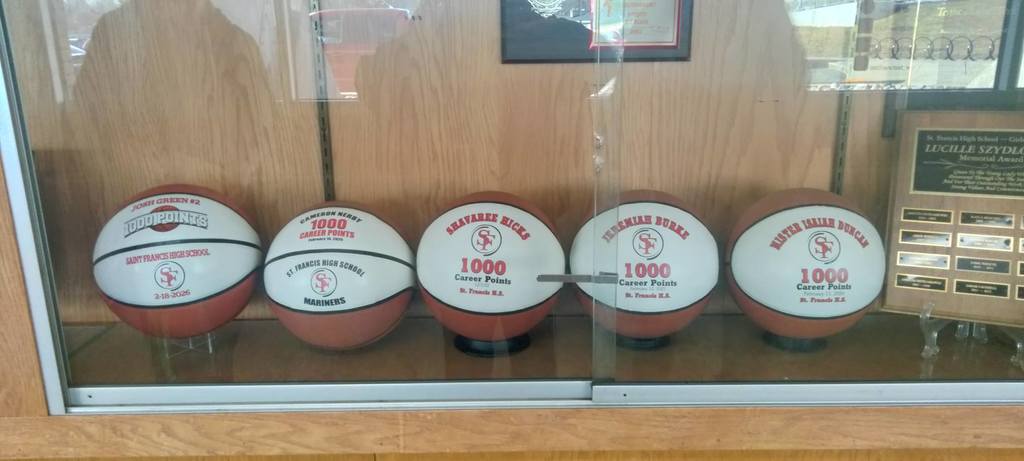 Five 1000 point basketballs in a tropy case