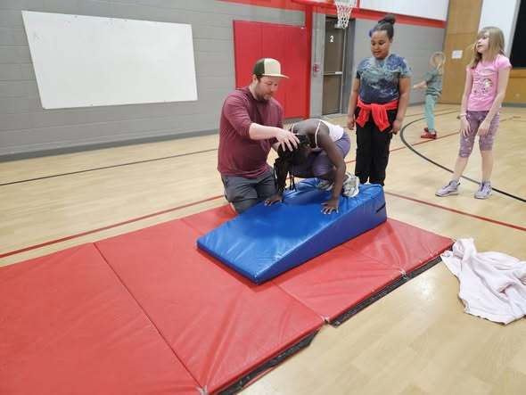 Teacher helping student use tumbling mat