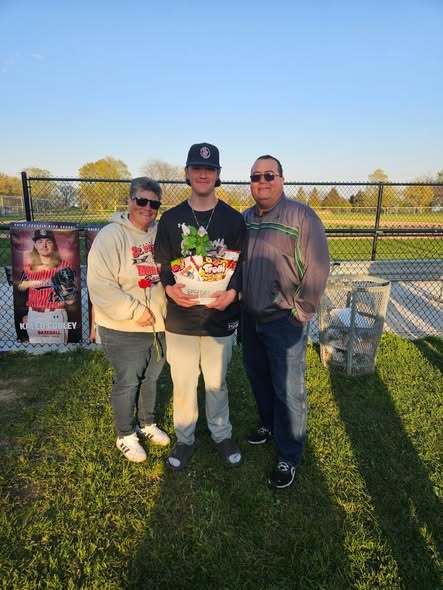 Senior Night baseball with a senior and his parents behind the bench