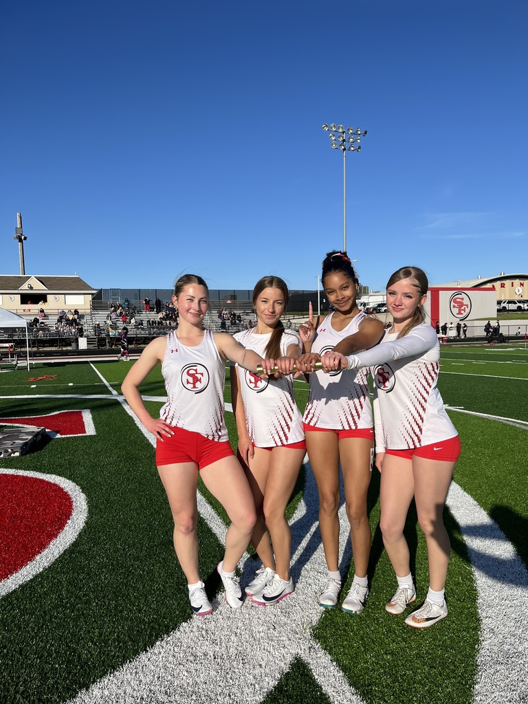 Relay team on the field all holding the baton. 