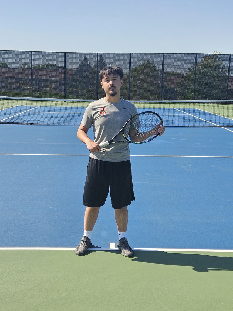 Student on tennis court holding a racket. 