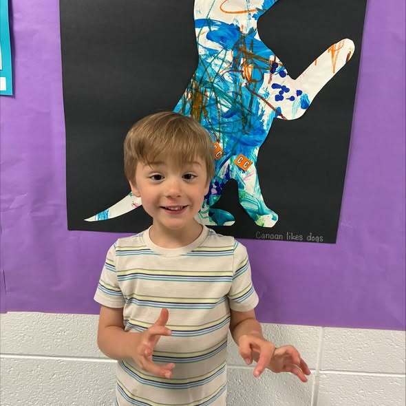 Early childhood student standing next to artwork