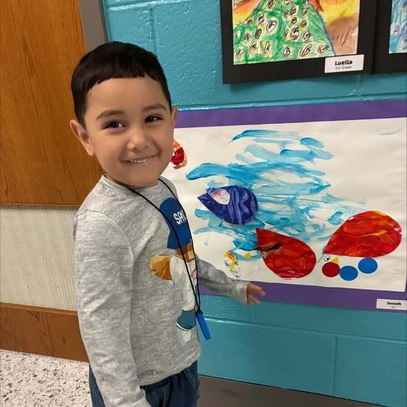Early childhood student standing next to artwork
