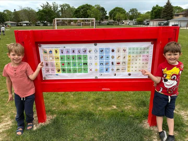 Two students, one on each side, of new outdoor communication board